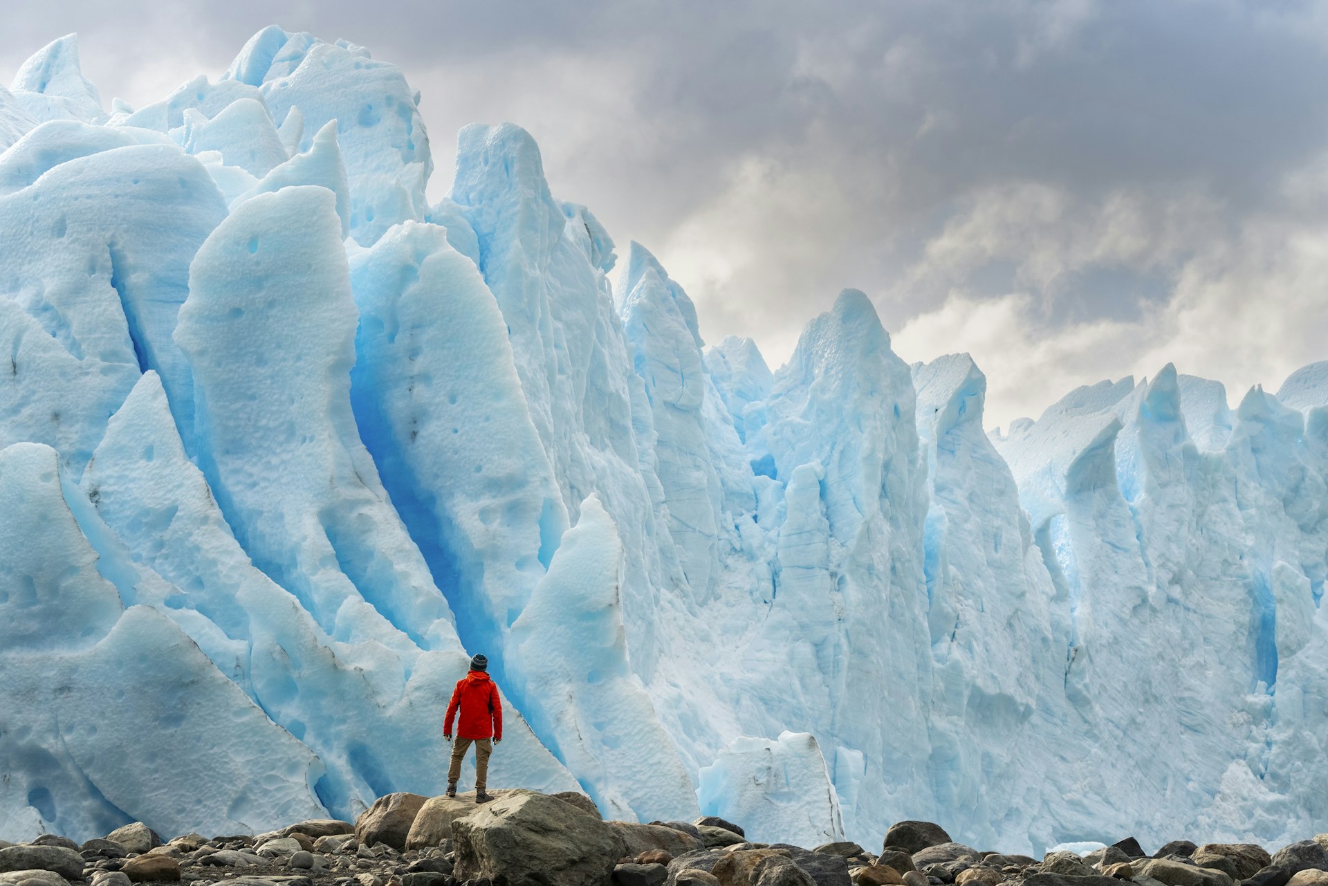 Close-up of a man standing in front of blue ice formations at Perito Moreno, Santa Cruz province, Argentina.