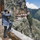 An Asian tourist photographing the Tiger's Nest Monastery in Bhutan