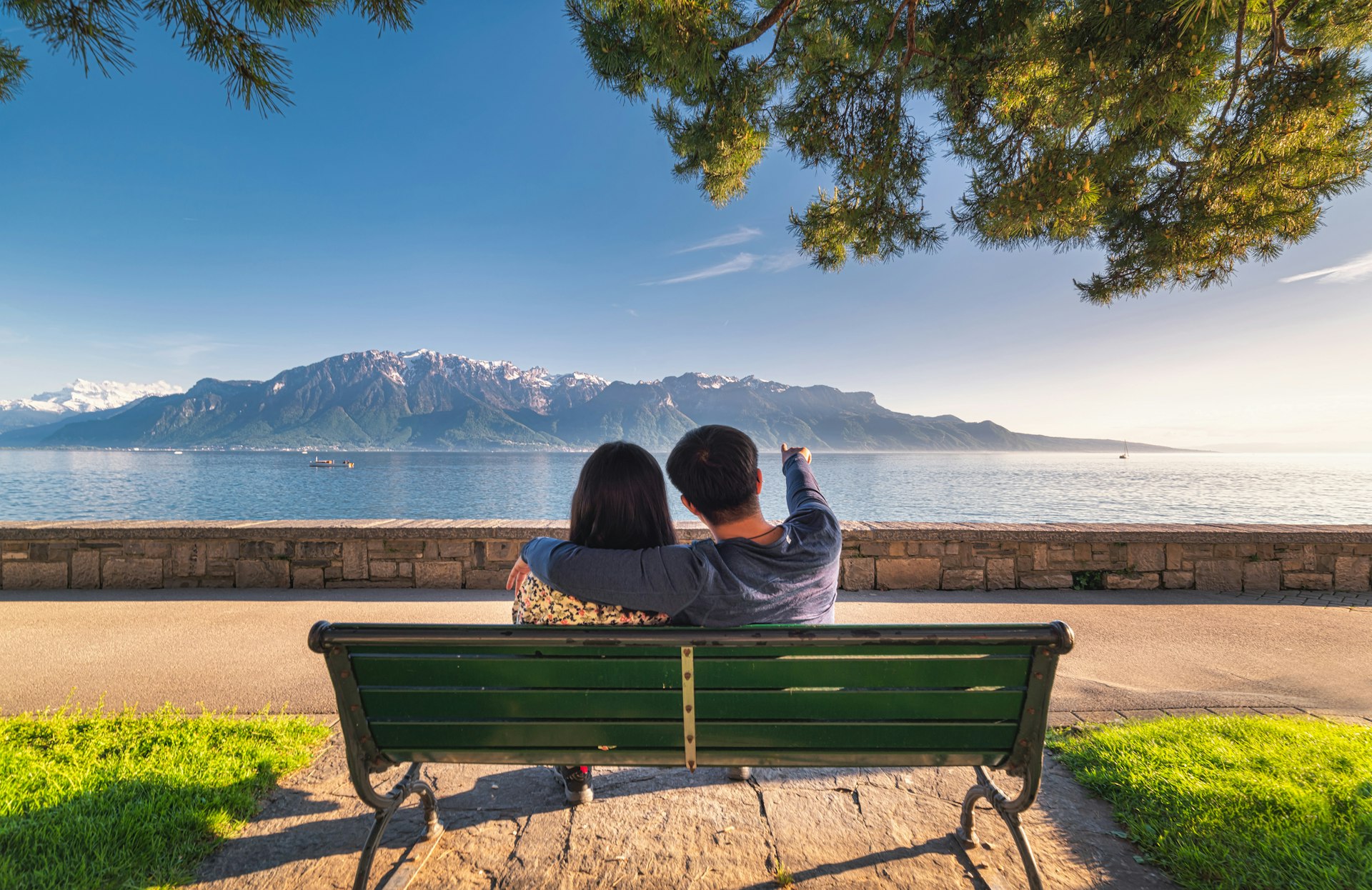 Portrait of Couple Love Tourist are Sitting in Public Garden Bench While Looking at Beautiful Scenic Nature Landscape at Lake Geneva, Vevey, Switzerland.