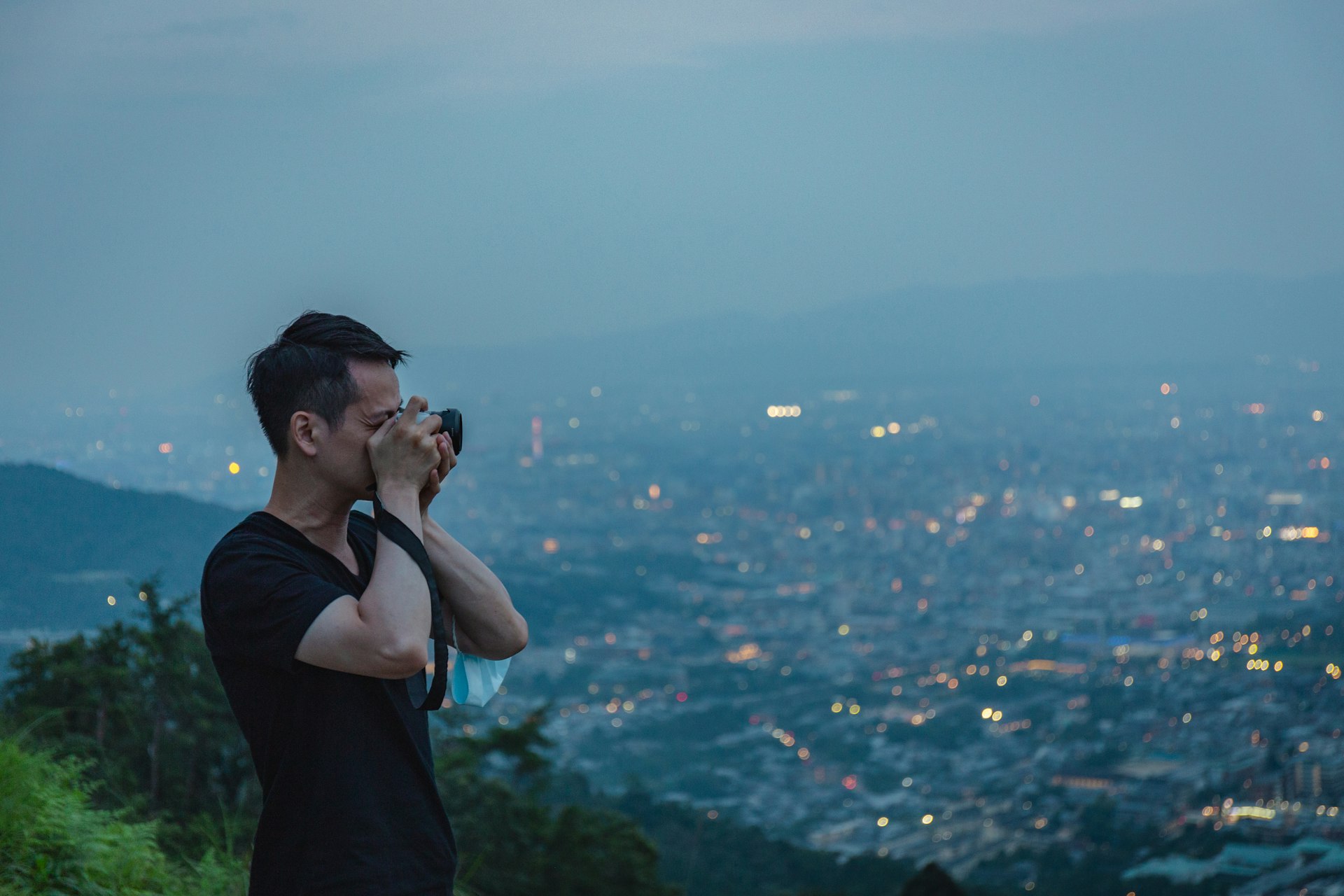 Asian man taking photos from the top of Mt Daimonji in Kyoto, Japan