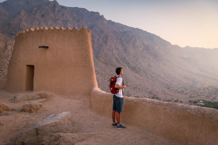 Man visiting middle eastern Dhayah Fort in north Ras Al Khaimah, United Arab Emirates on the desert mountain top at sunset. Caucasian man traveling to Middle East
1286976886