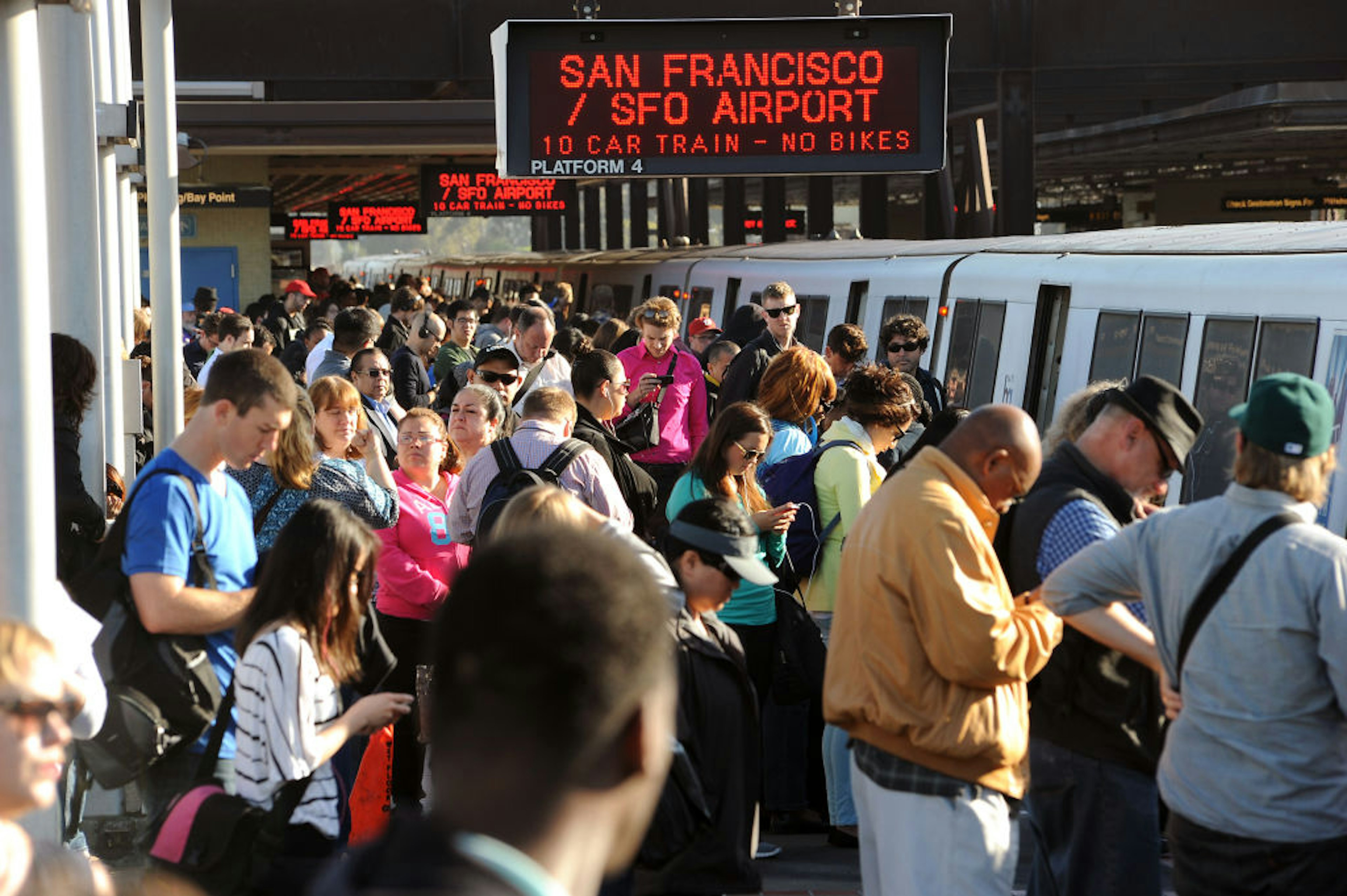 A bustling scene at a transit station with a crowd of commuters waiting on the platform