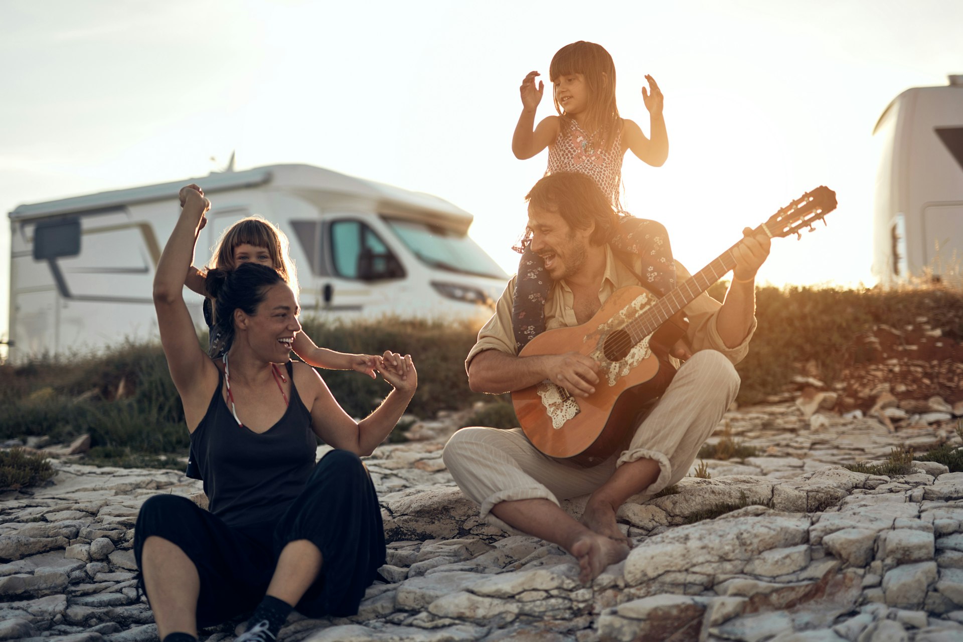 A family singing together on a beach in Croatia with their camper van parked in the background