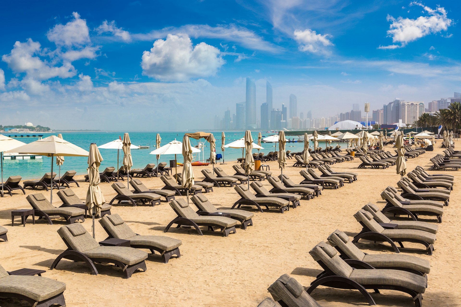 Sunbeds and umbrellas at the beach of a luxury hotel in Abu Dhabi, United Arab Emirates, on a summer day.