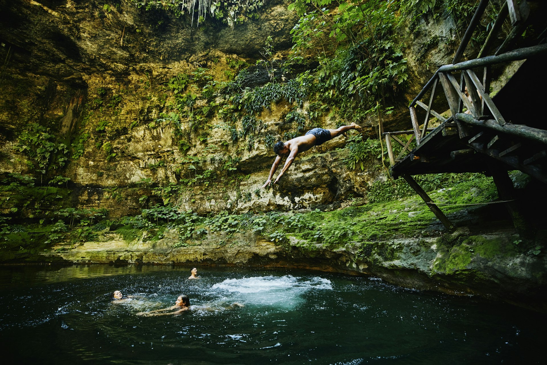 A man dives into a cenote - a sunken water hole - to join friends swimming there