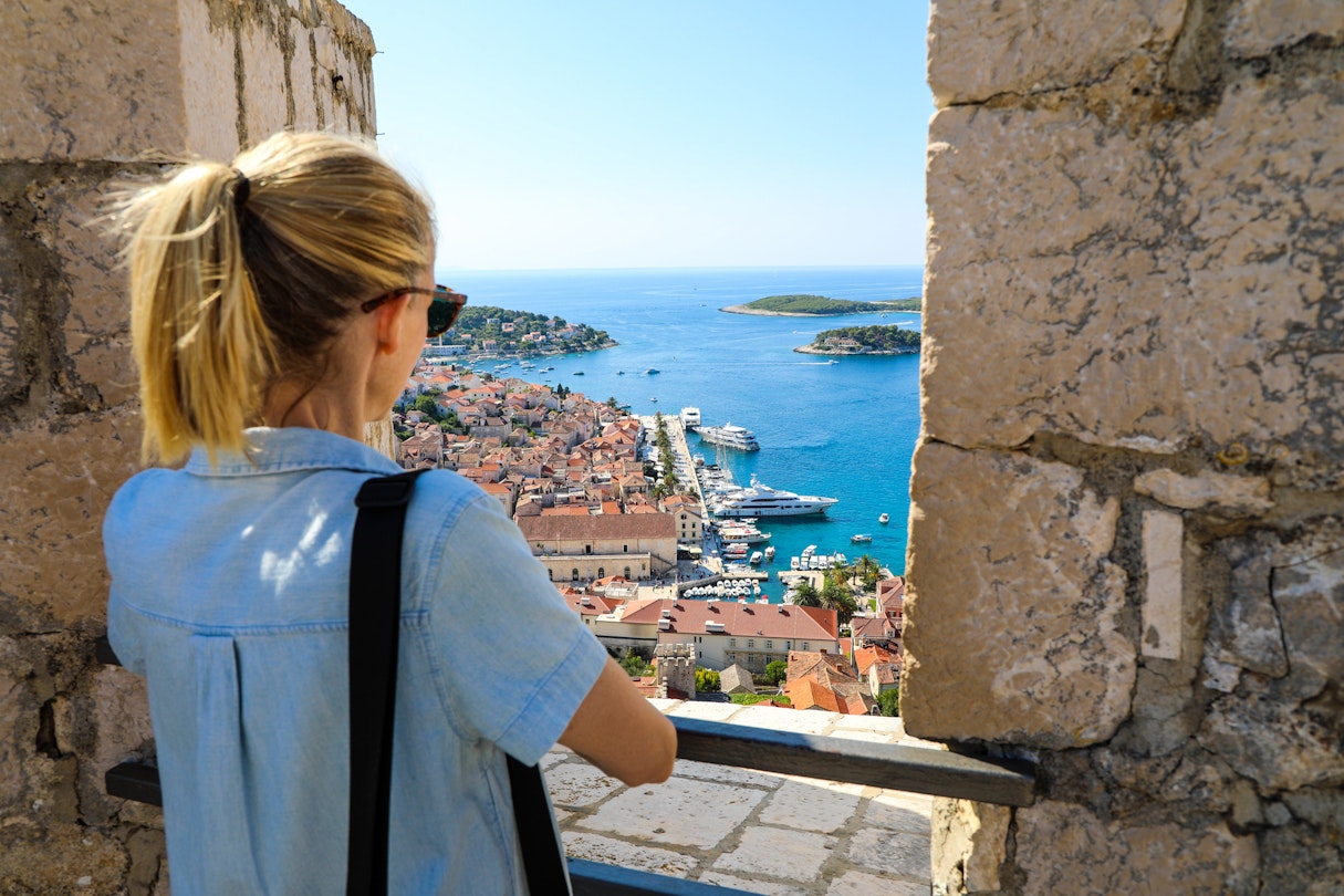 Blonde woman tourist enjoying view of Hvar harbor from Spanish fort