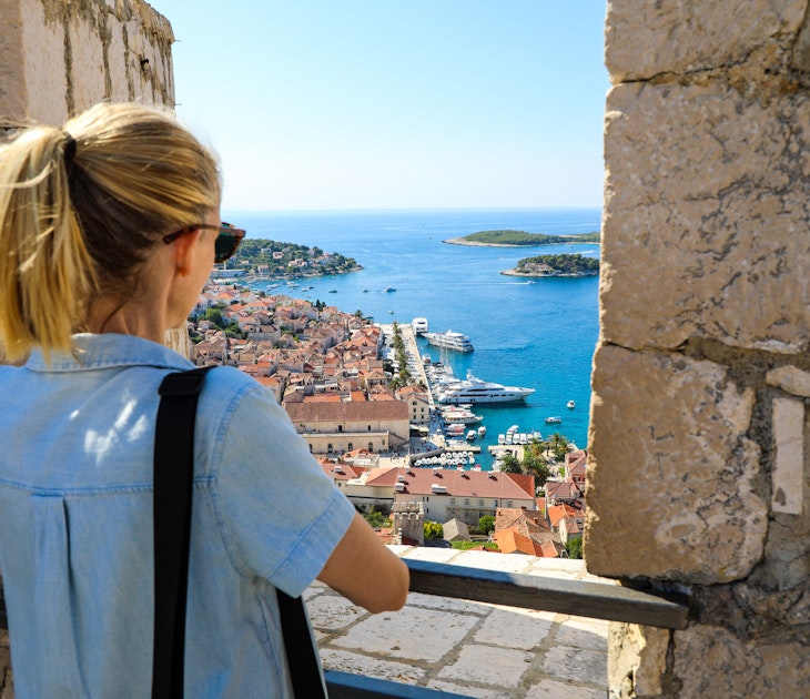 Blonde woman tourist enjoying view of Hvar harbor from Spanish fort