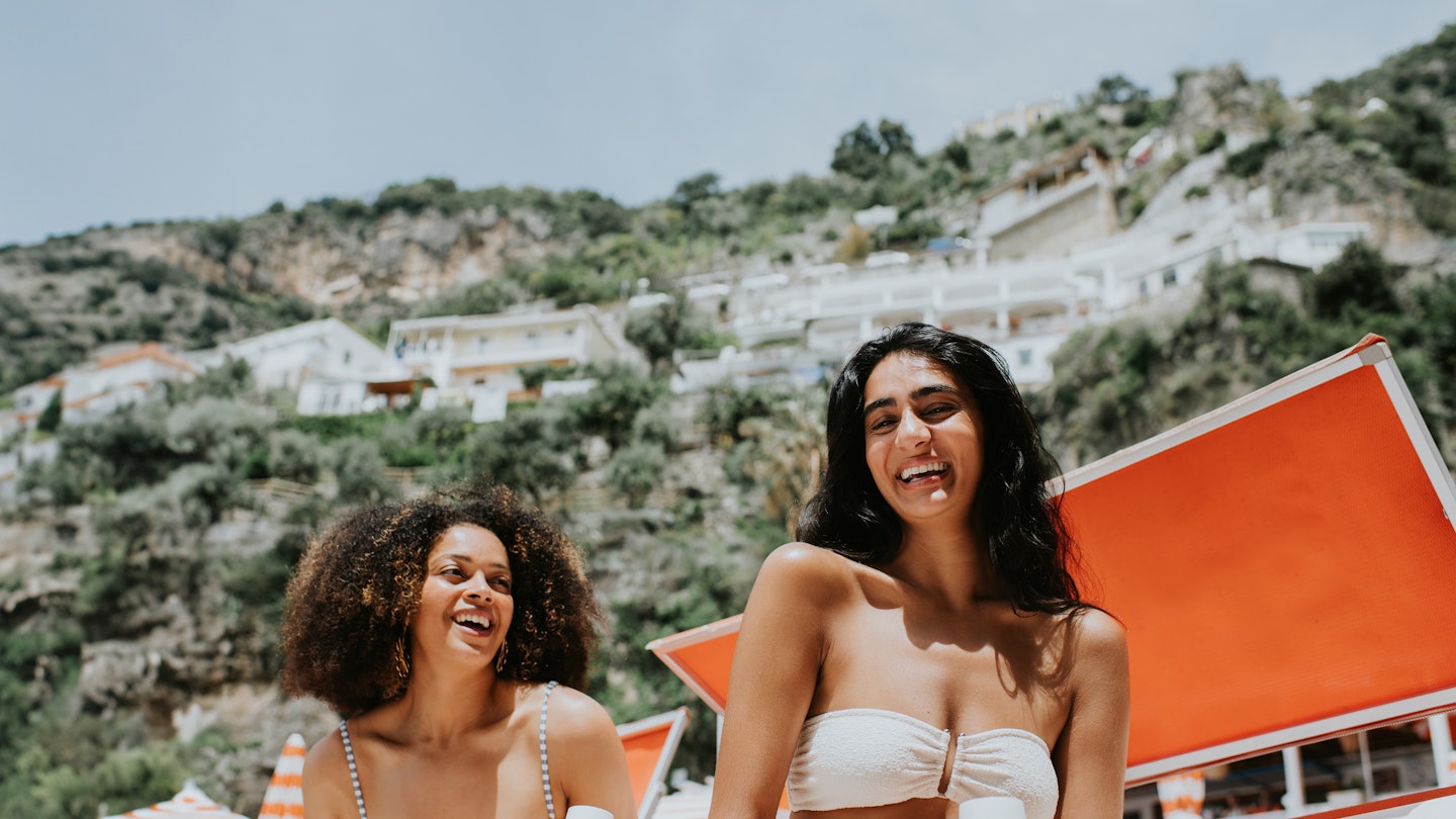 Two women laughing together on a beach on the Amalfi Coast