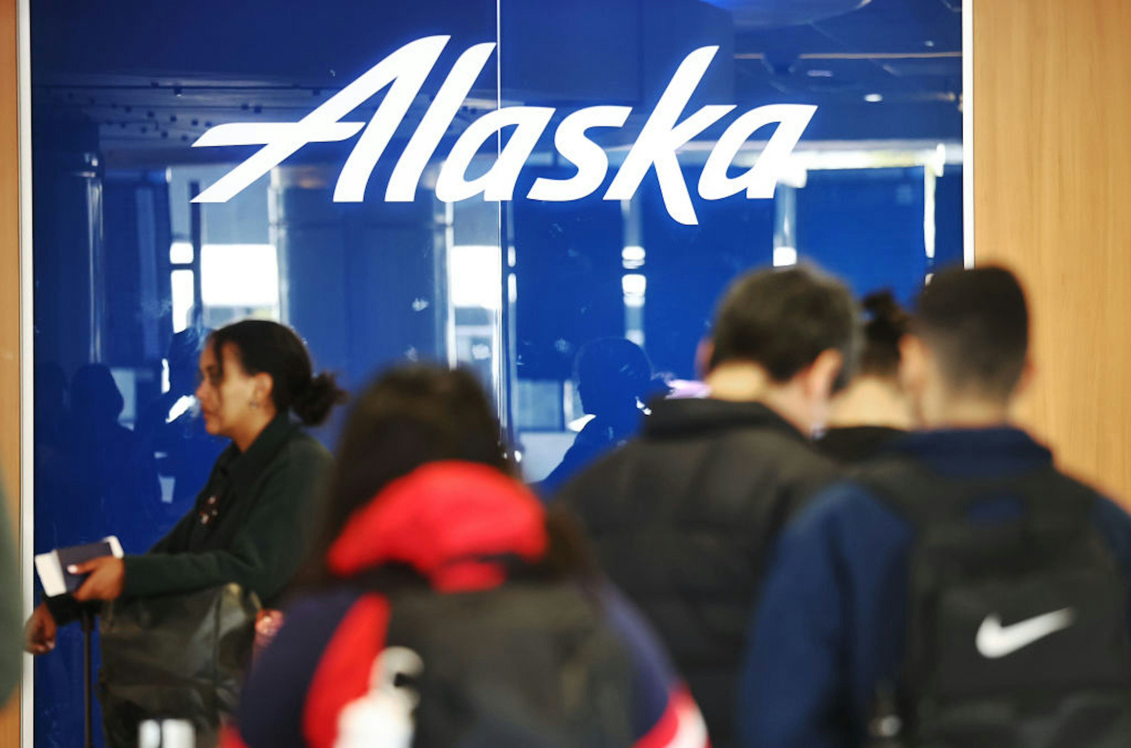 The Alaska Airlines logo is displayed as travelers stand at a check-in area at Los Angeles International Airport (LAX) on January 8, 2024 in Los Angeles