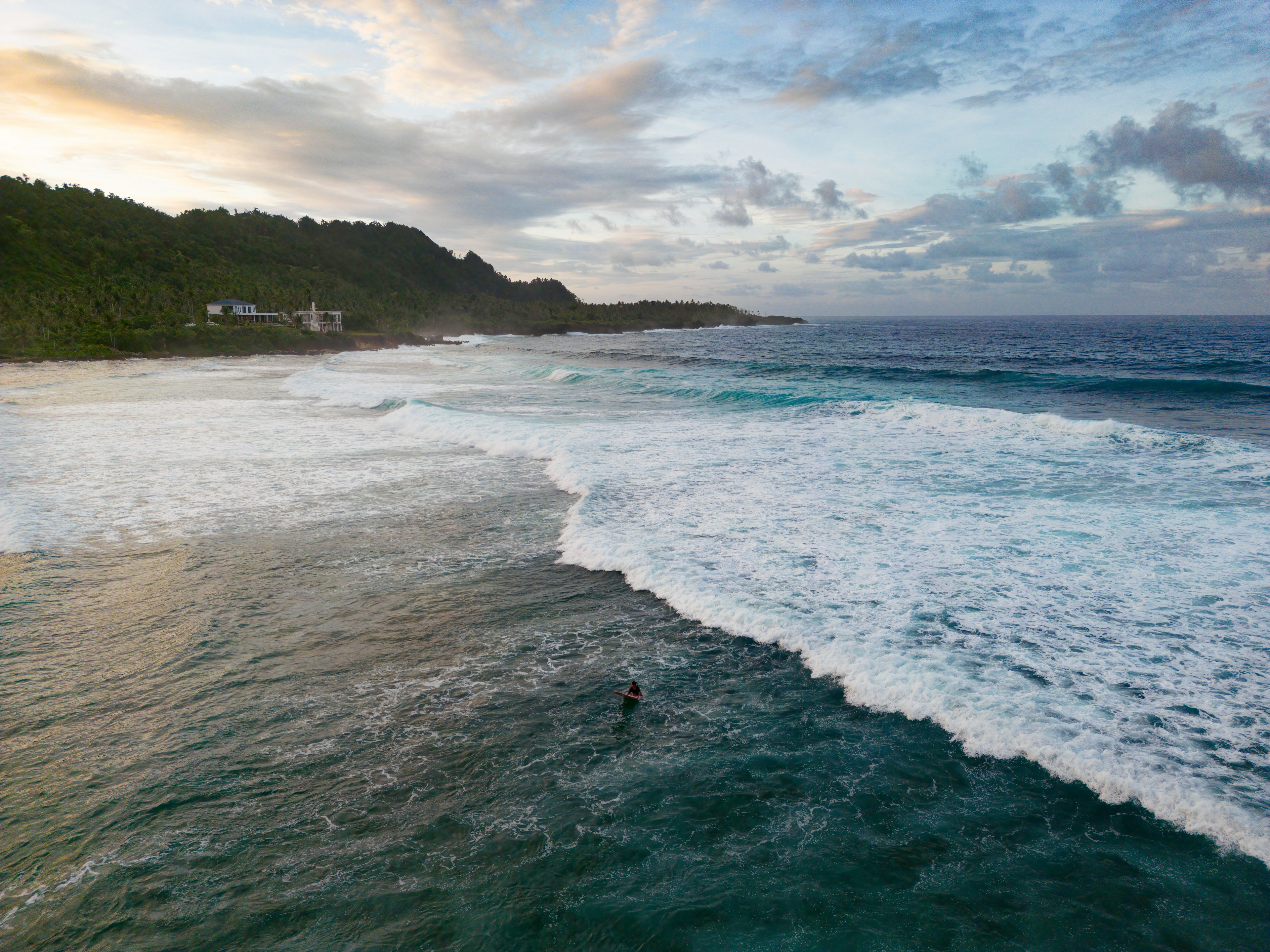 An aerial view of a surfer at Pacifico beach, Siargao, Philippines