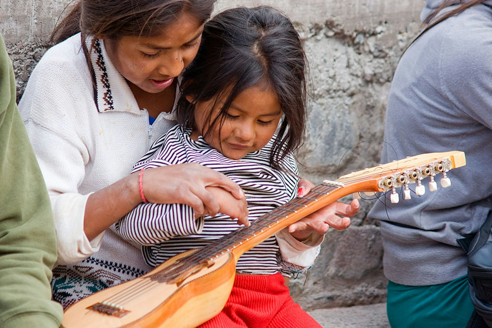 Little Quechua girls playing with a charango, an Andean lute instrument in Iruya (Argentina). Iruya is a beautiful but very remote village in the Quebrada de Humahuaca, in Northern Argentina