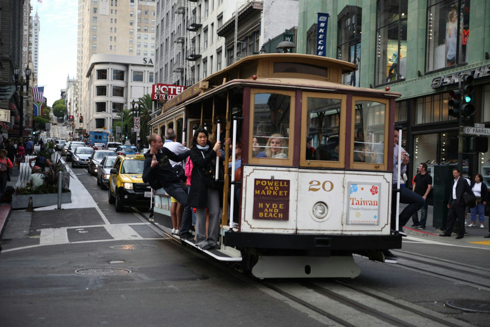 A historic cable car full of passengers makes its way up a steep street in San Francisco