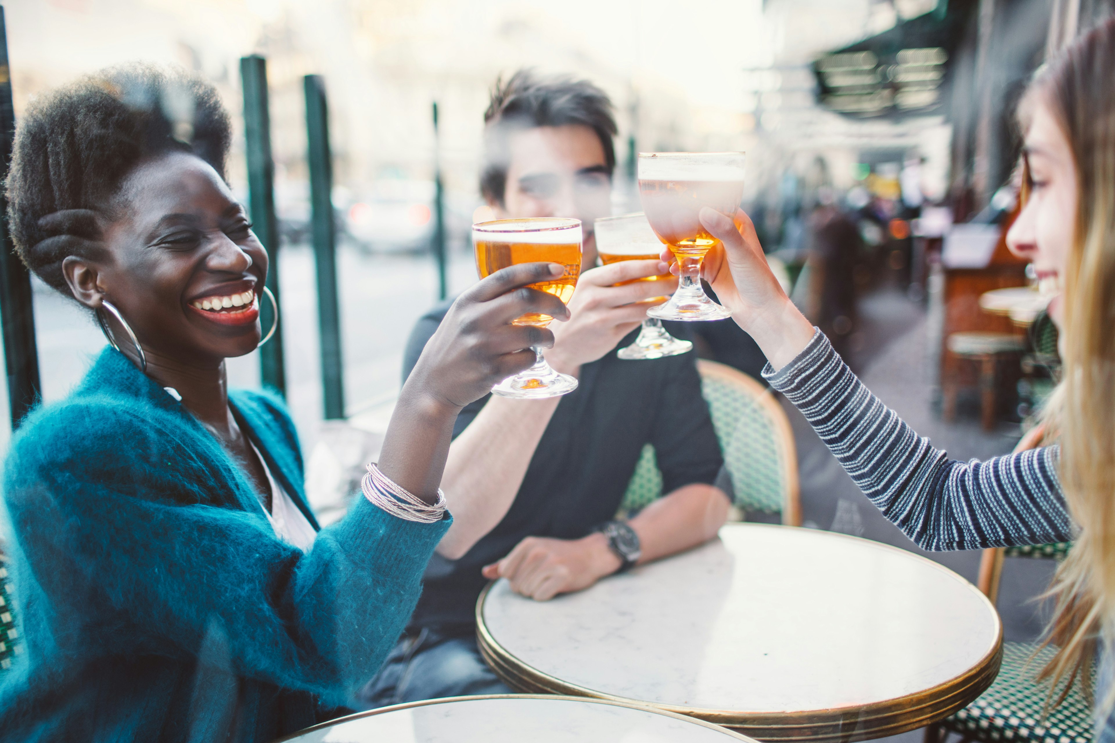 Three friends drinking beer together at a French cafe/bar