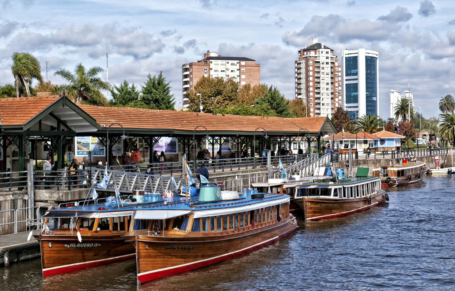 A cityscape of Tigre, showing tourists on a boat-lined wharf.