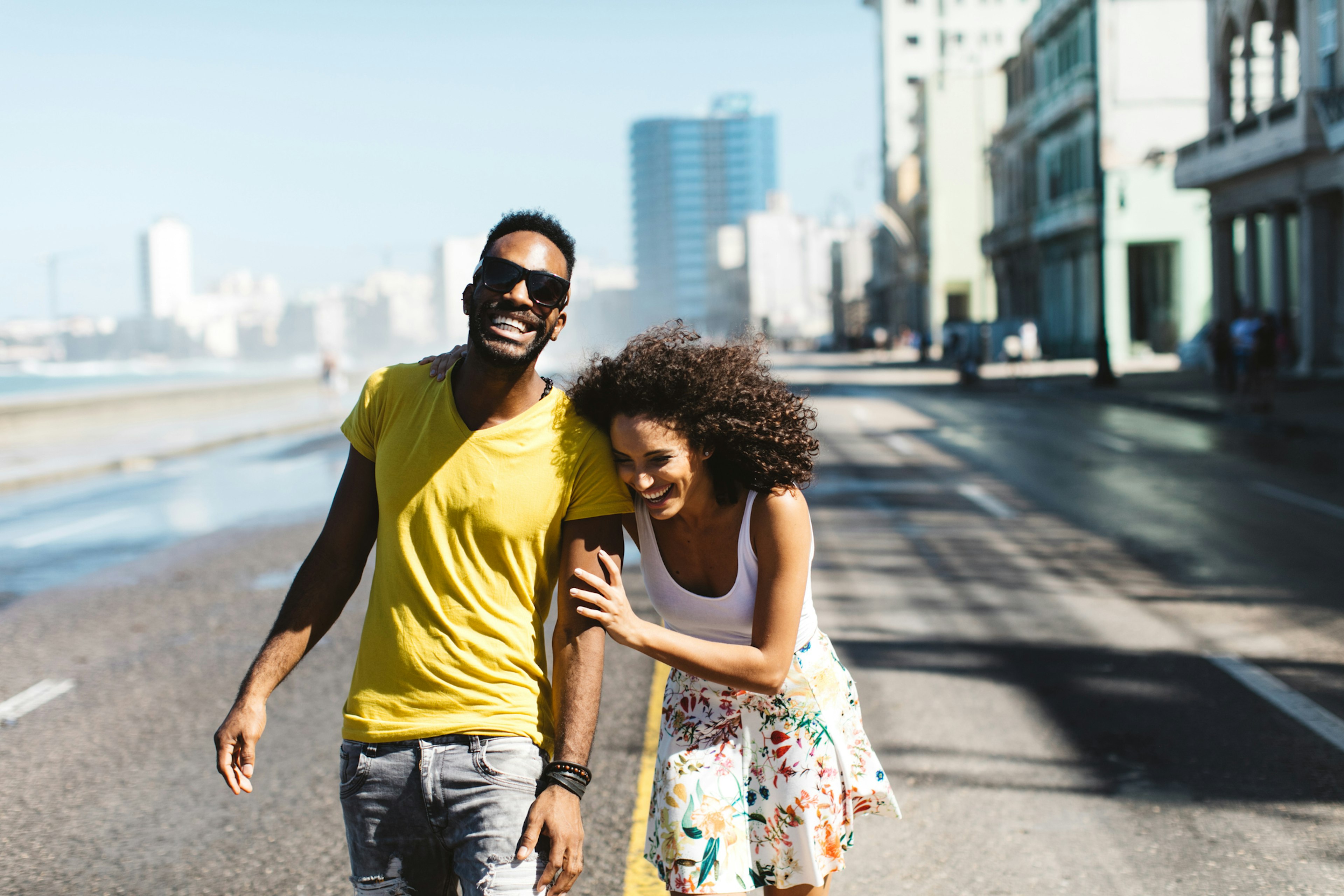 A laughing Cuban couple walking along the streets of Havana in the sunshine