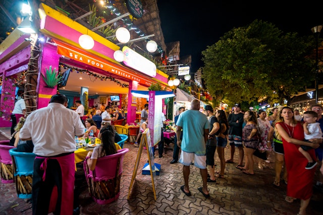 People waiting at the restaurant entrance at busy dinner time on 5th Avenue, shopping street on Playa del Carmen, Cancún