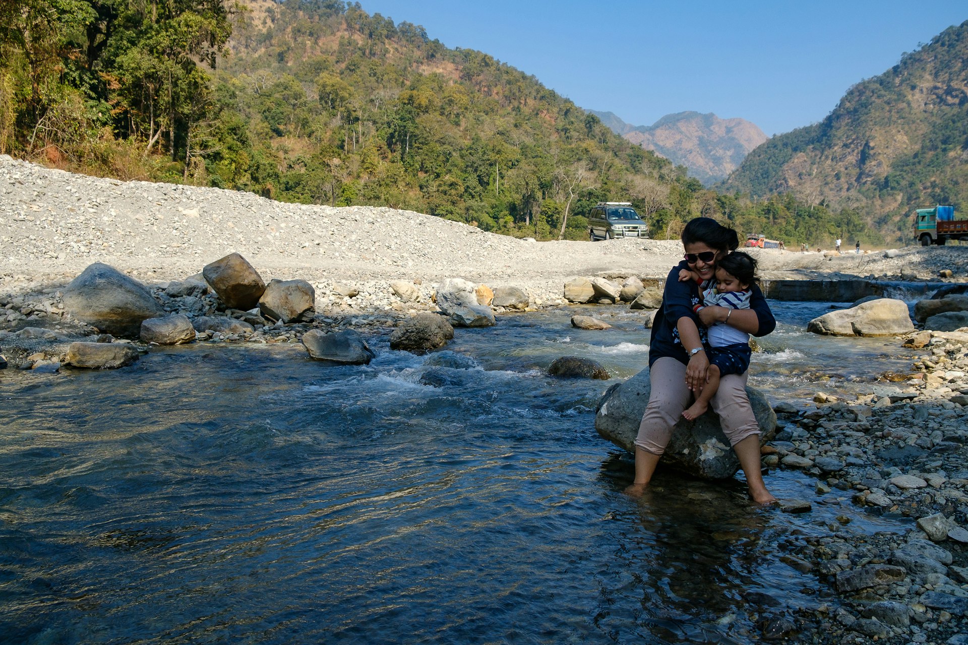 Woman and toddler paddling in a stream in the mountains