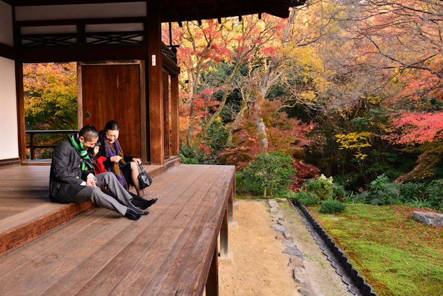 Japanese family of father and mother in their 40’s and their 7 year old daughter are enjoying autumn foliage at the corridor of Hojo (the living quarters of head priest) of Tofuku-ji Temple, Kyoto, Japan..Tofuku-ji Temple, which was founded in 1236, is the head temple of the Tofuku-ji School of Rinzai Sect of Zen Buddhism