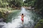 High angle view of carefree woman jumping into lake amidst forest in Costa Rica