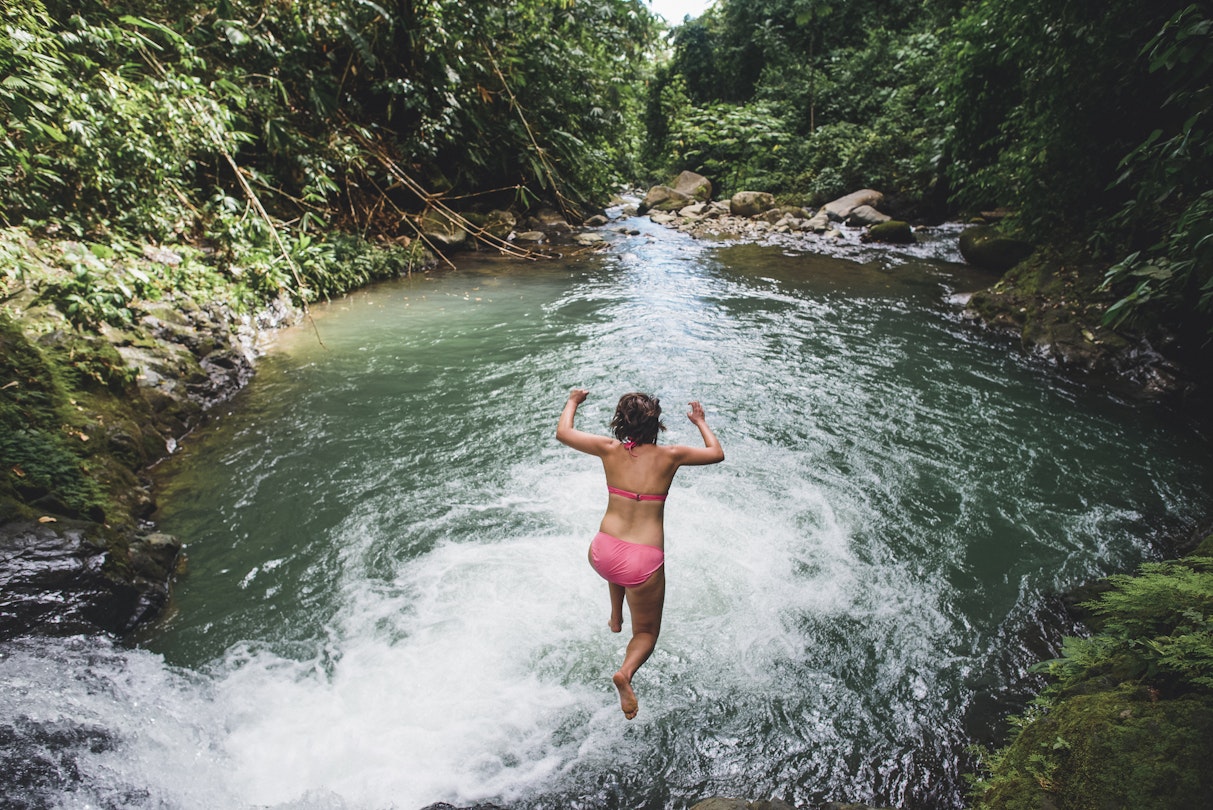 High angle view of carefree woman jumping into lake amidst forest in Costa Rica