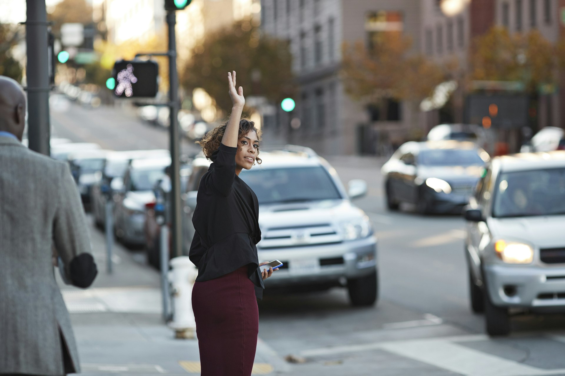 A young woman hails a taxi on a busy city street