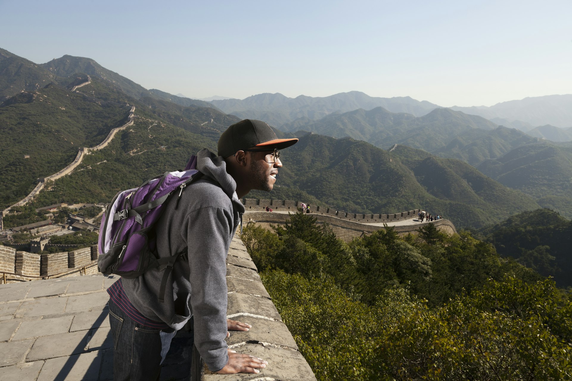 A young man looks off the side of the Great Wall of China