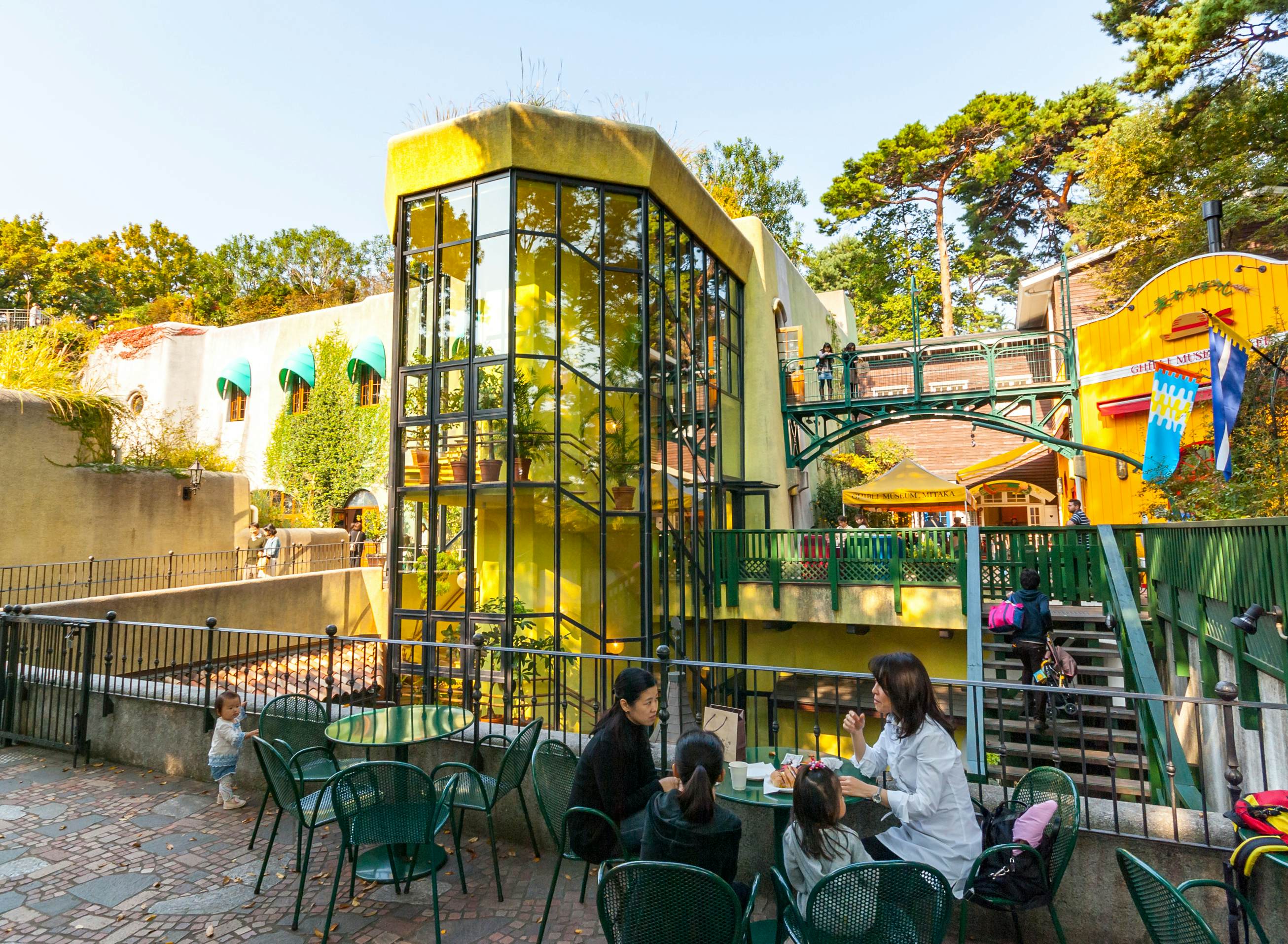 A family sits at a table in an outdoors museum complex with a toddler standing nearby