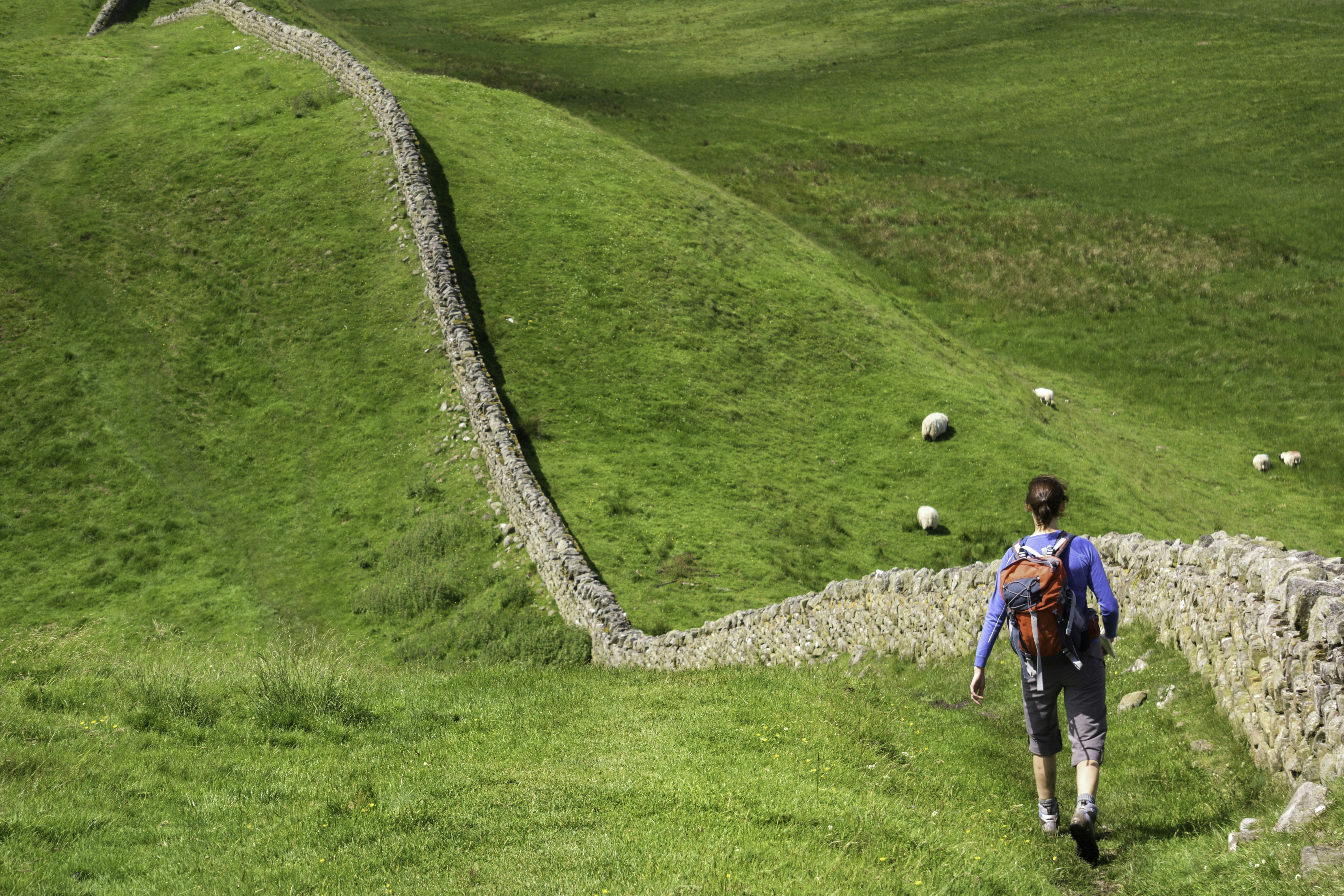 A hiker walking alongside Hadrian’s Wall near Crag Lough in Northumberland, England, UK