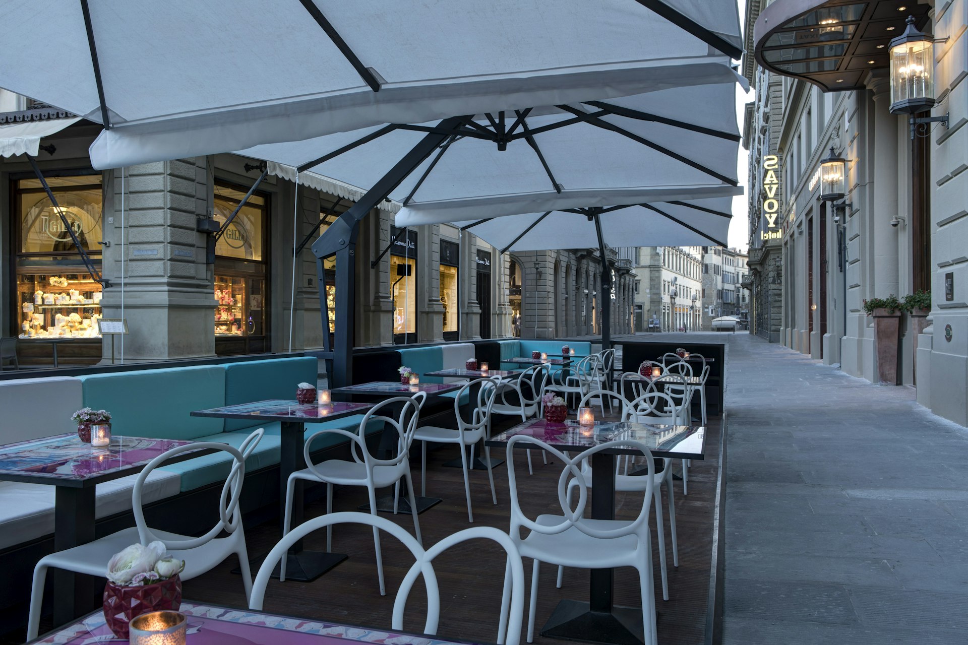 A terrace of tables and chairs on the street outside a restaurant  