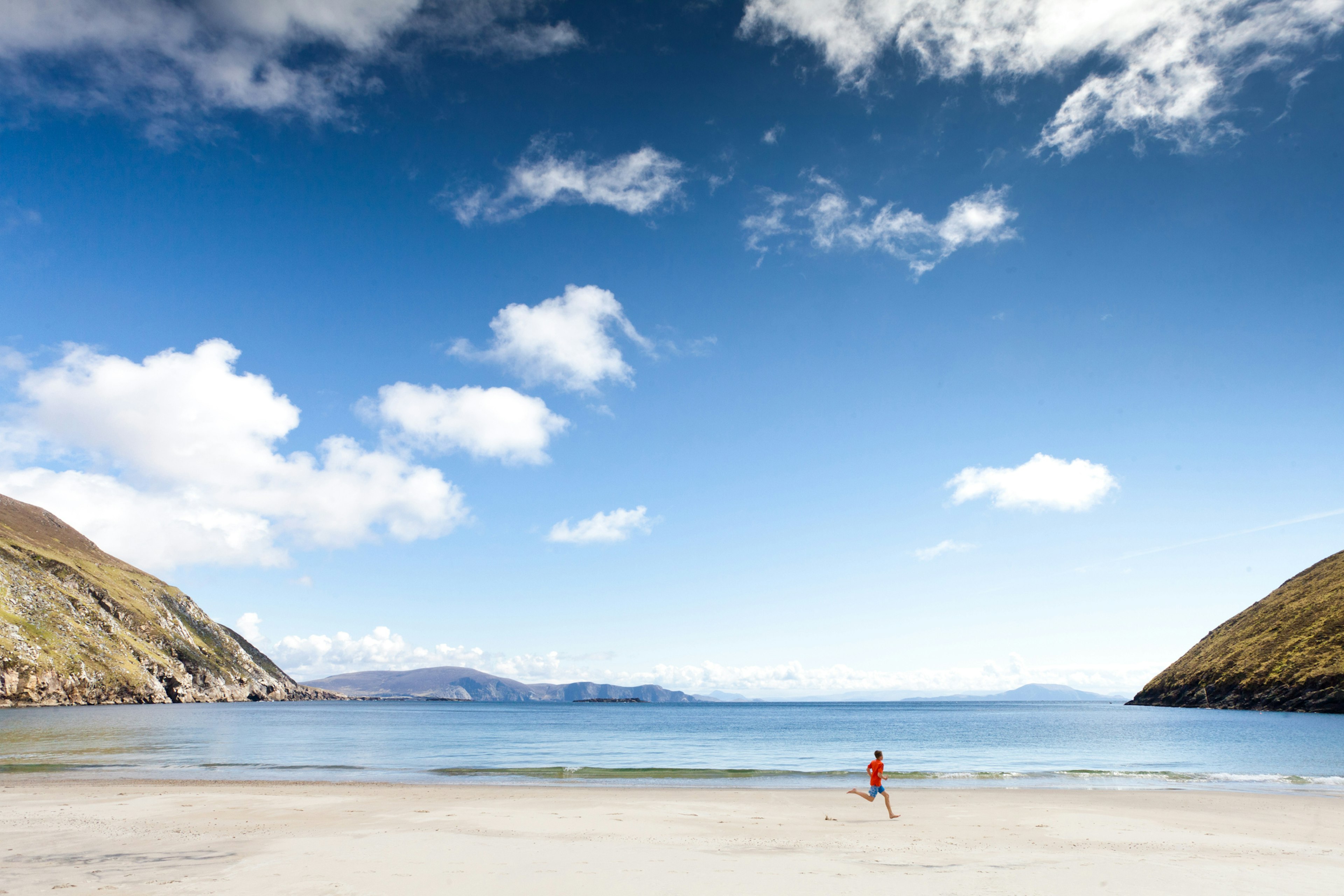 Boy running across beach at Keem Bay