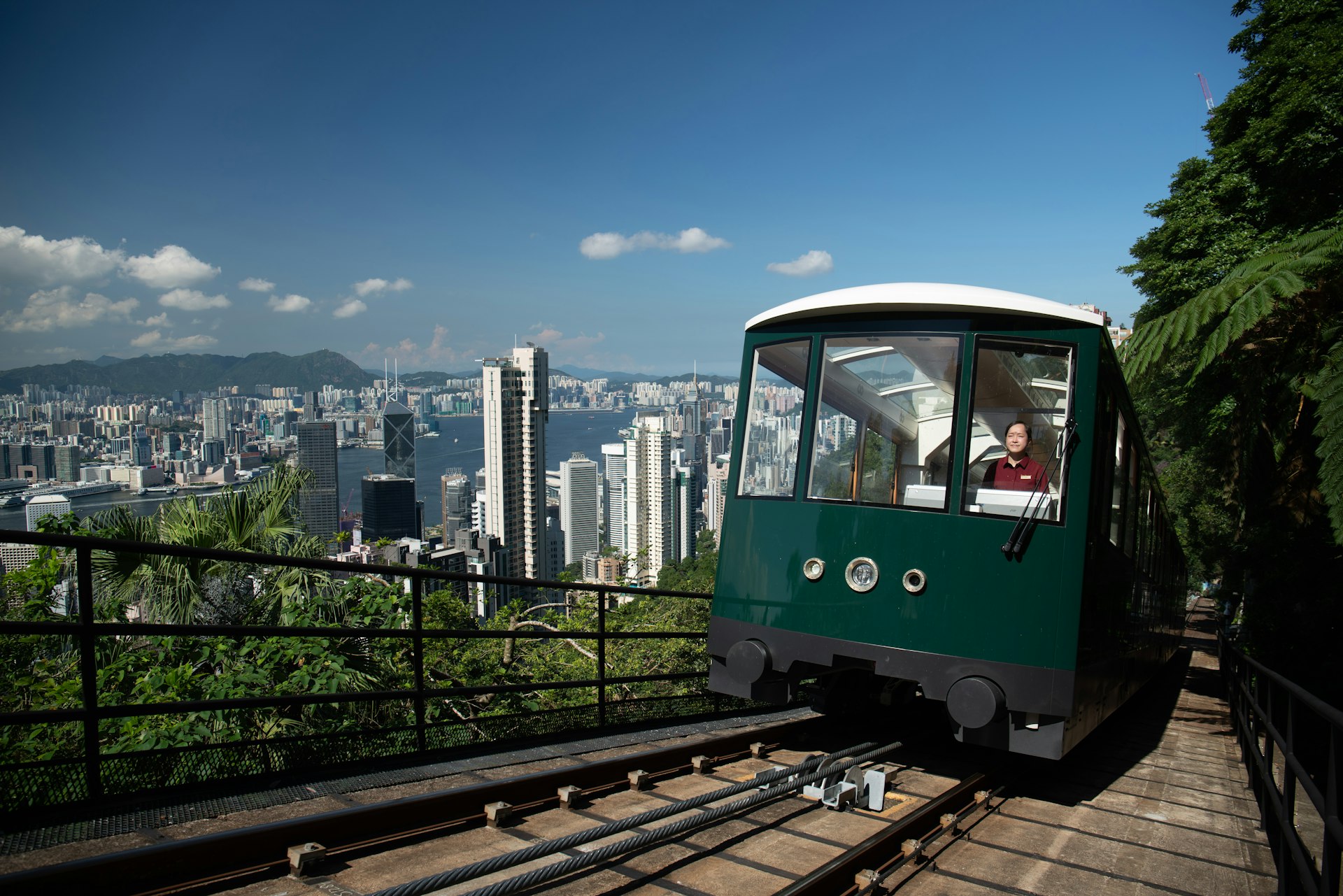 A funicular railway going up a steep incline surrounded by foliage. The tram is green with a glass roof