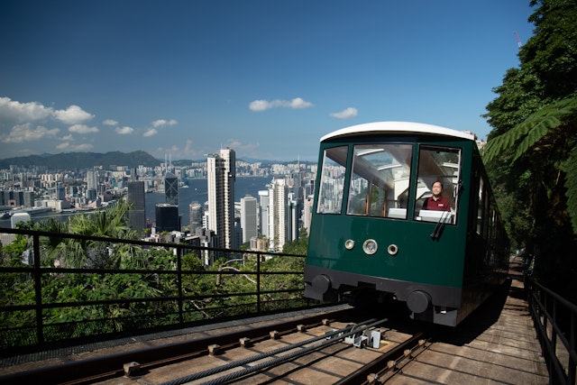 A funicular railway going up a steep incline surrounded by foliage. The tram is green with a glass roof