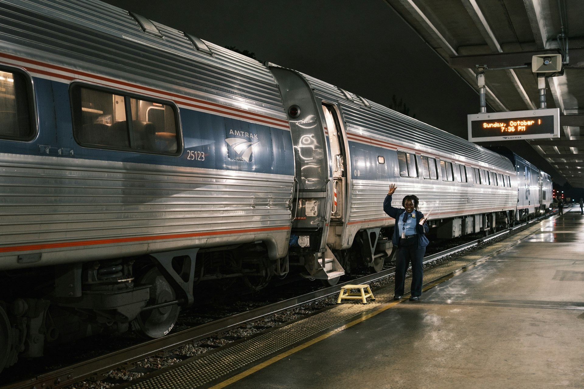 An attendent raises their arms as the Silver Meteor sits in Savannah having arrive in the dark of the early evening