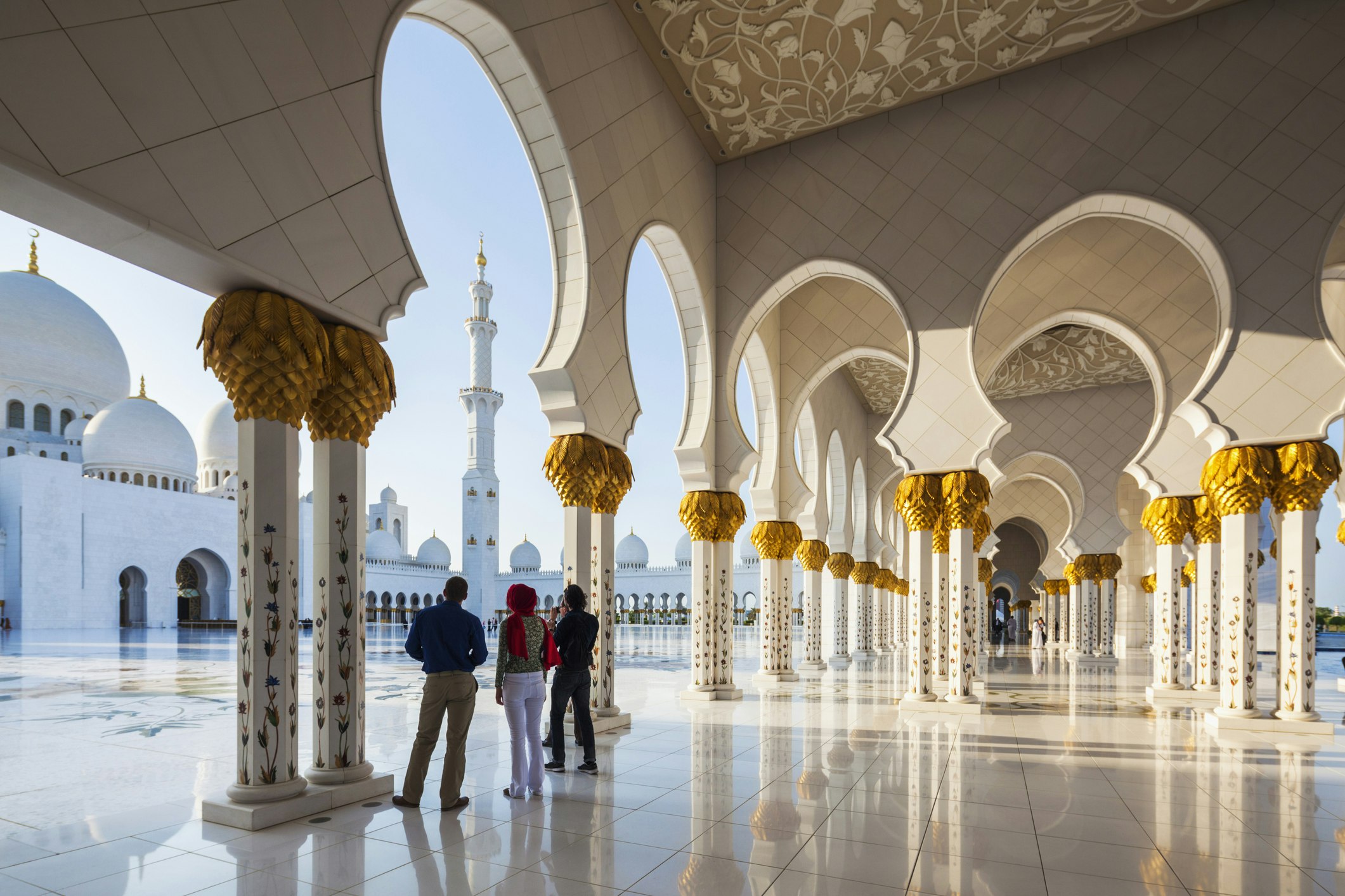 Decorative arches at Sheikh Zayed Grand Mosque, with a small group of visitors in the foreground