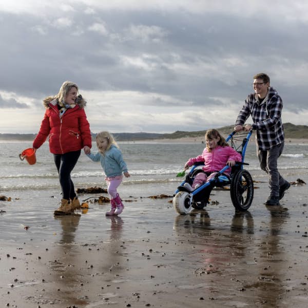 A family with a wheelchair user on a beach