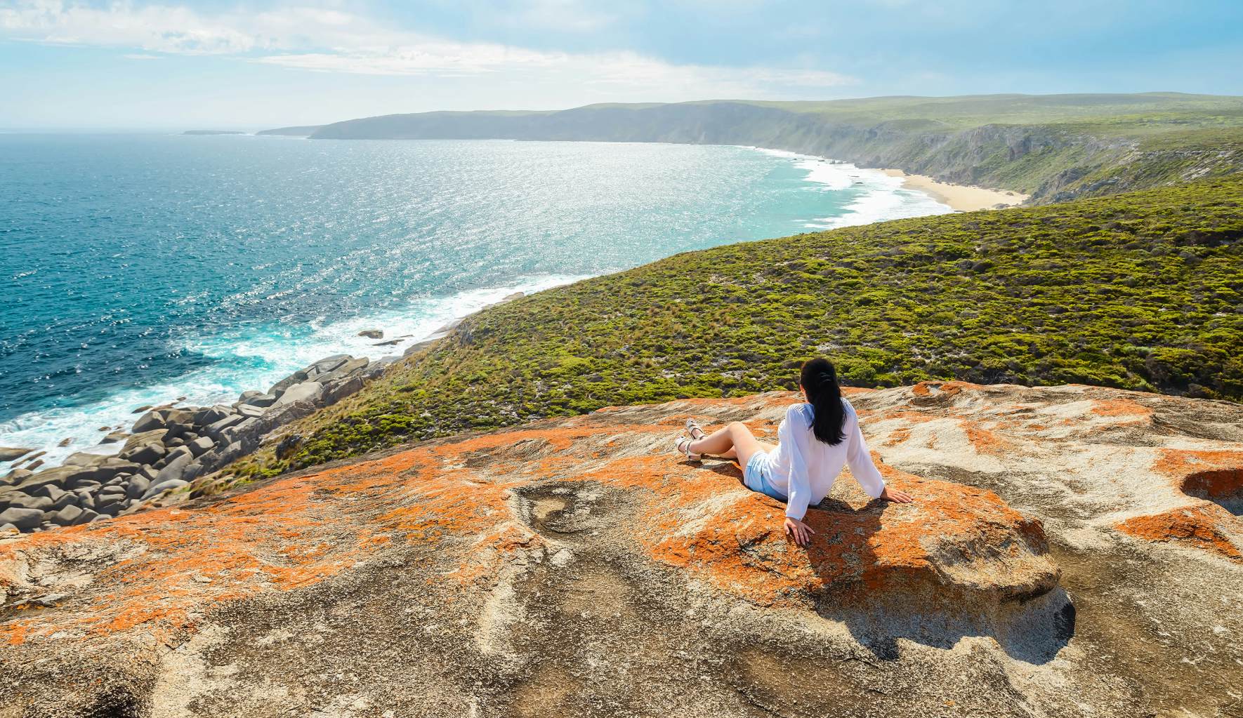 Person looking out over ocean and green hills