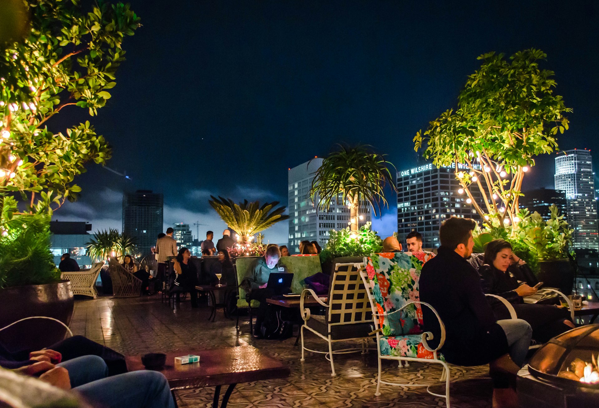 People at tables at dusk at a rooftop bar, Los Angeles, California, USA