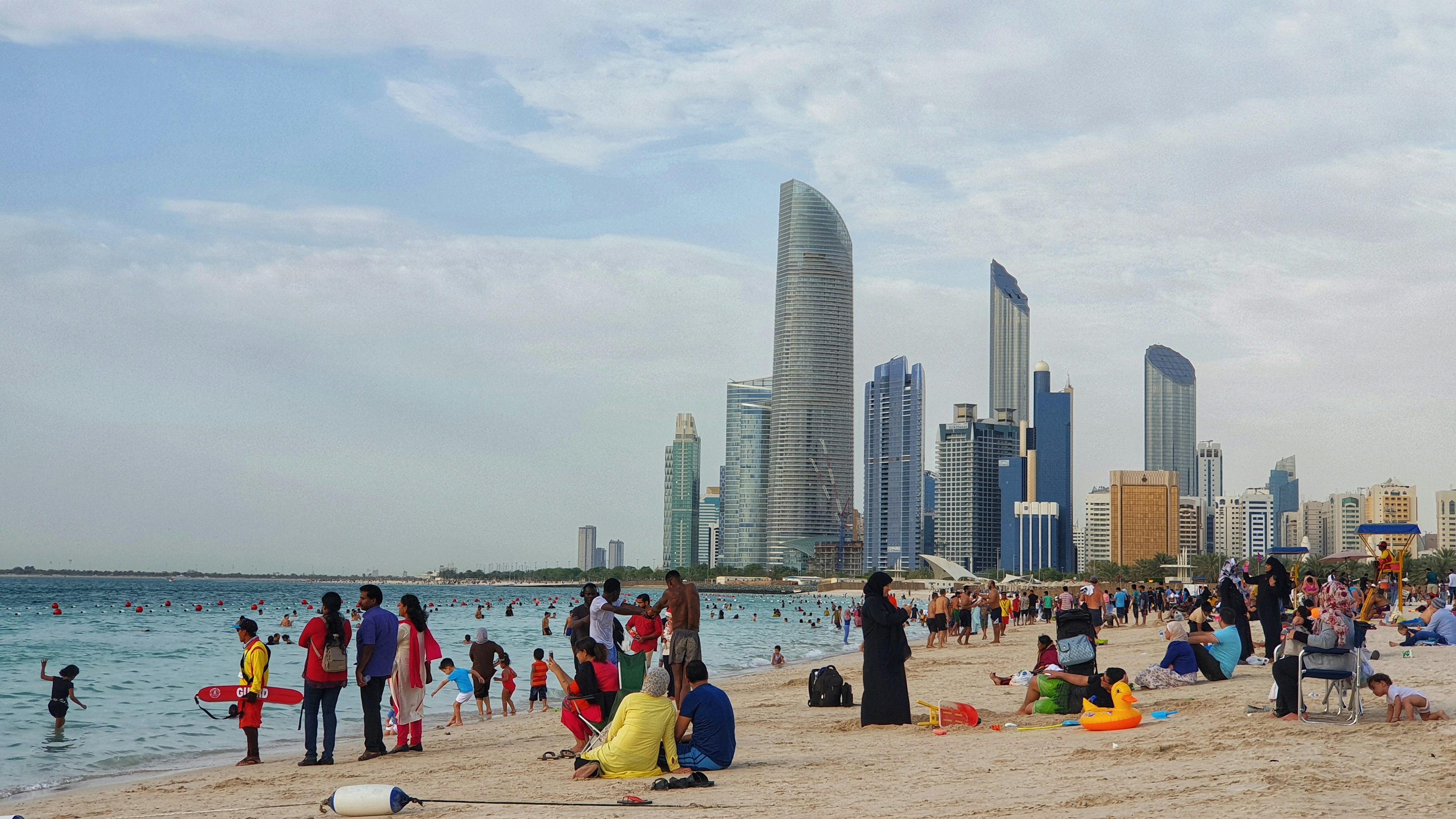 People in swimwear and people wearing clothes that cover their bodies fully enjoy time on the beach