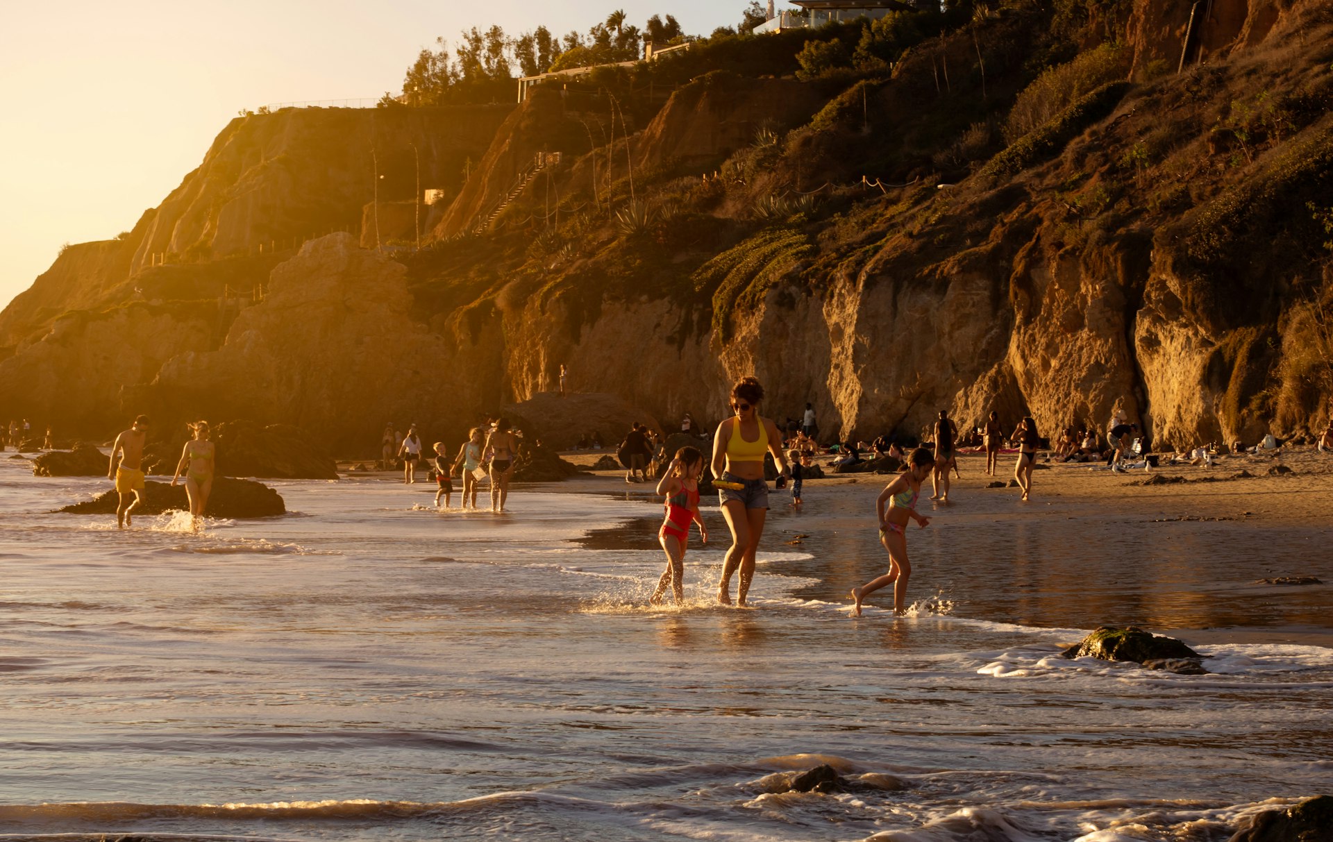 Vista do pôr do sol de pessoas se divertindo na praia El Matador, Malibu, Califórnia, EUA