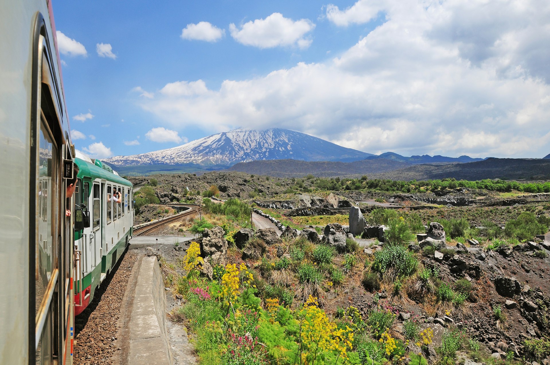 A train moves down a track toward Mt Etna, Sicily, Italy
