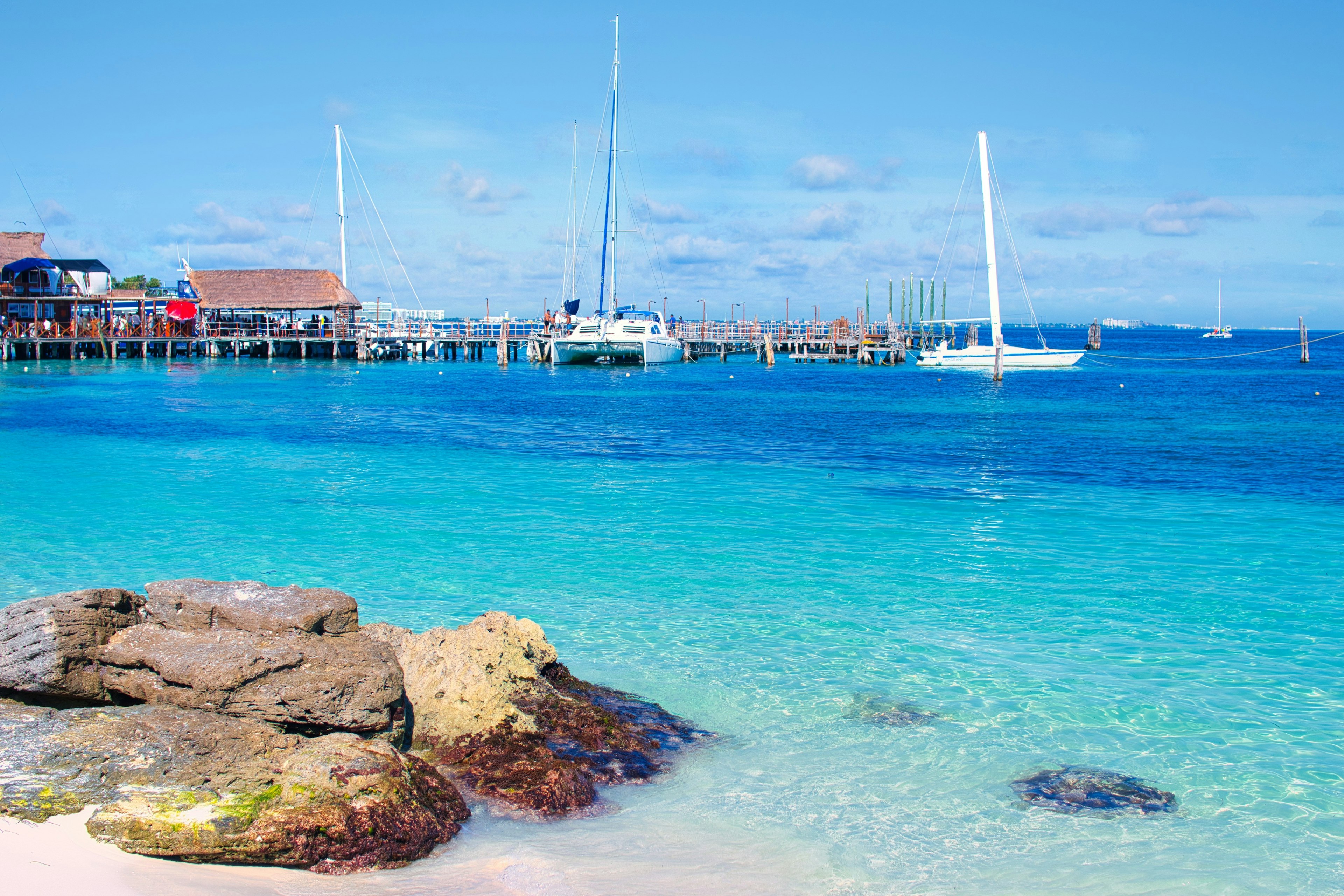 Rocks on the beach with sailboats in the distance, Playa Tortugas, Cancún, Quintana Roo, Mexico