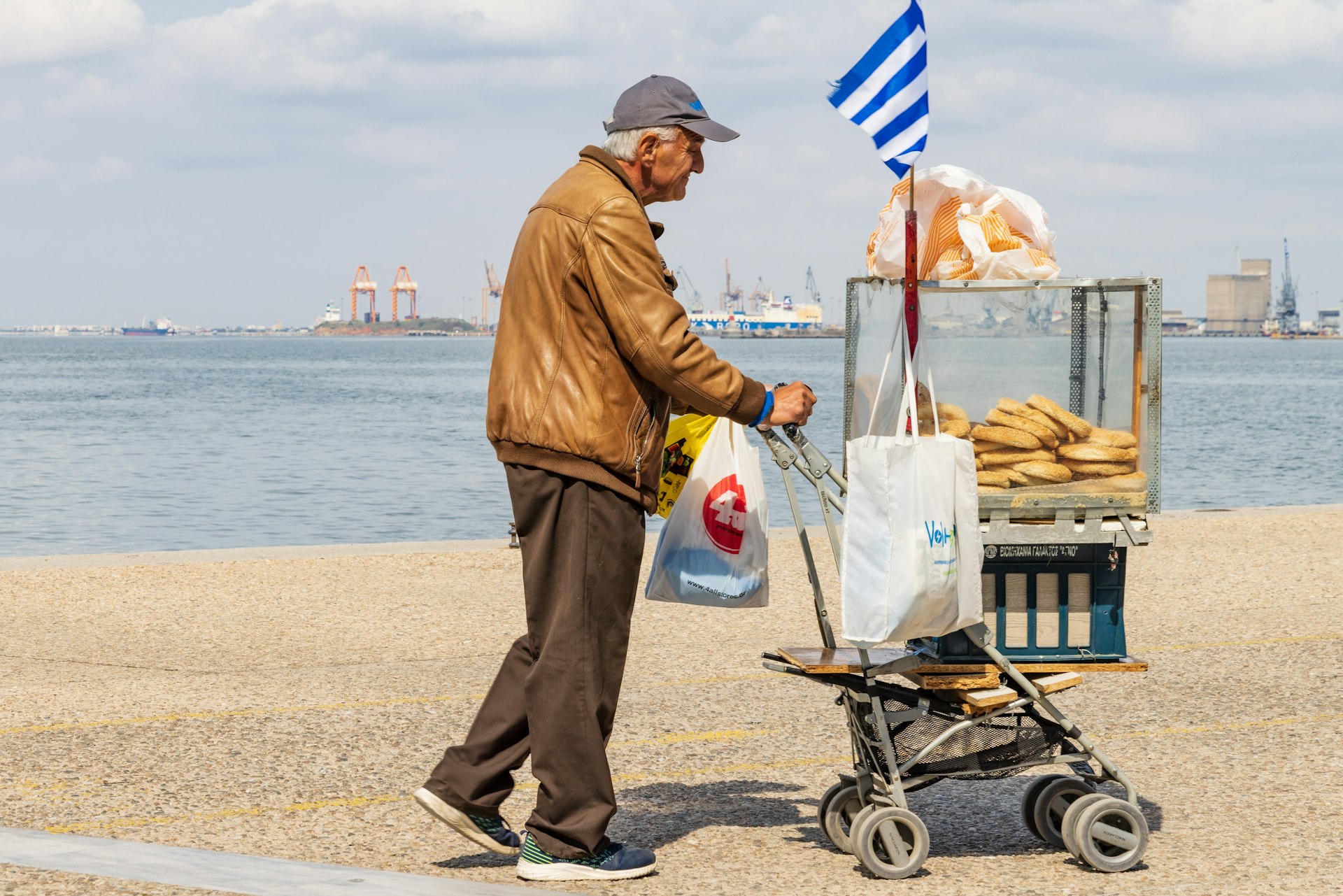 A man pushes a cart with koulouria rolls by the waterfront Thessaloniki, Macedonia, Greece