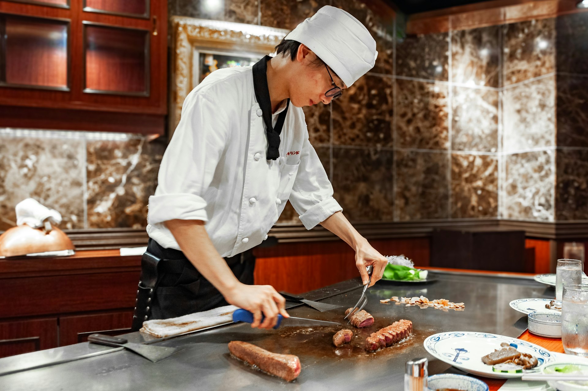 Young chef cutting wagyū (beef) meat at a restaurant in Kōbe, Japan