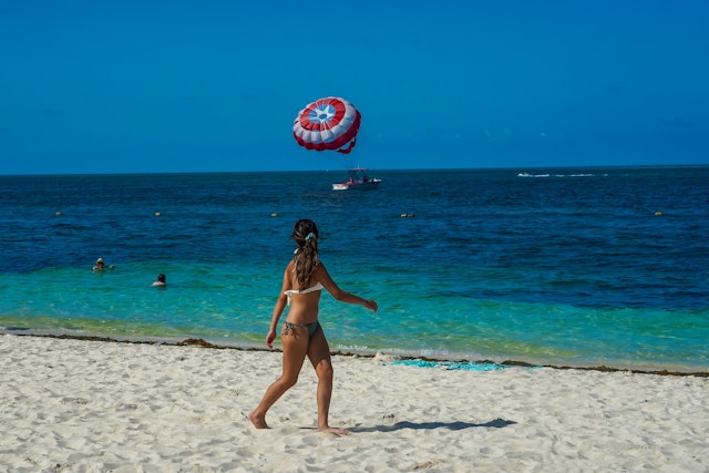 A woman walks on a sandy beach in the sunshine at the Playa Mujeres Beach in Cancún, Quintana Roo, Mexico