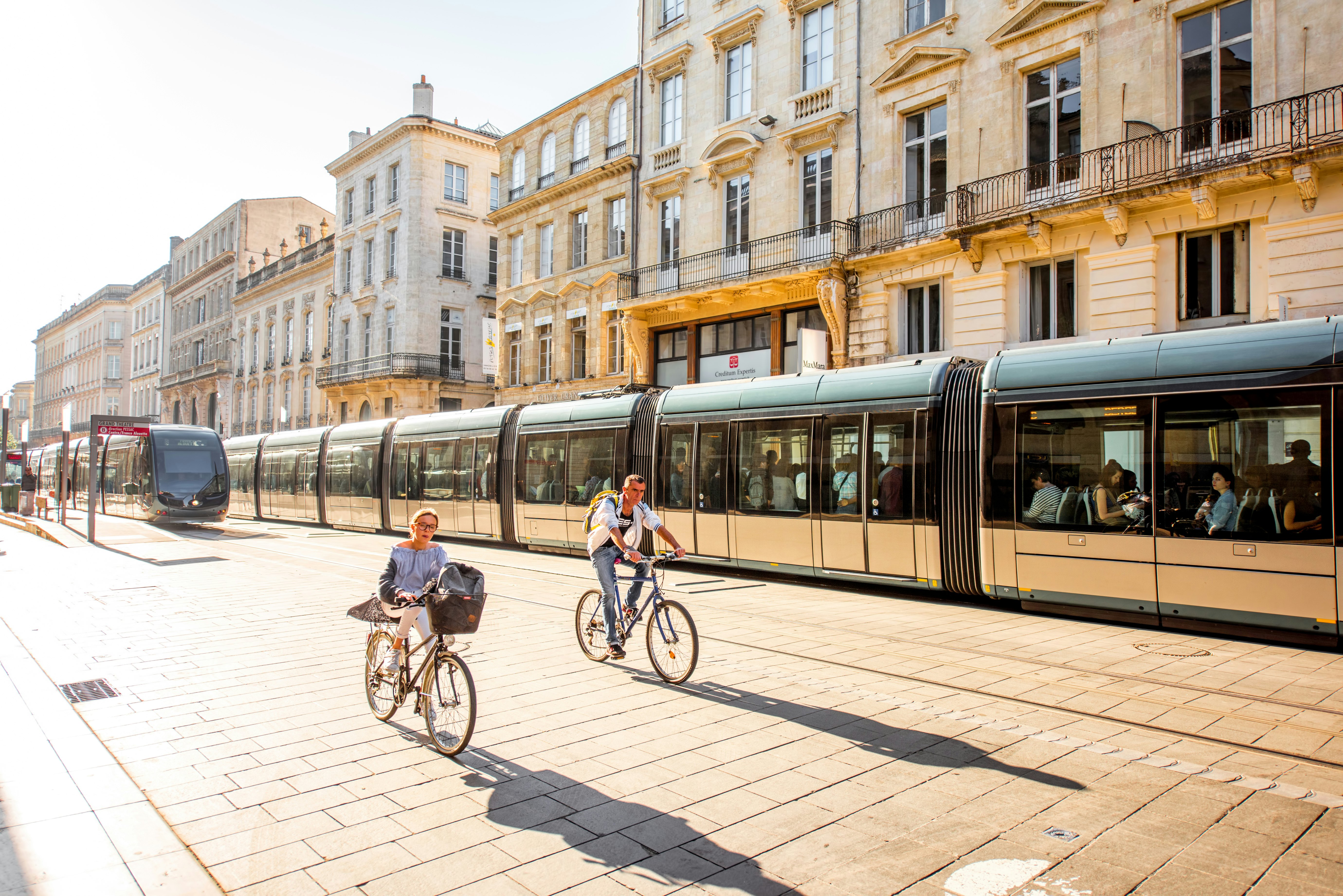 Street view with people two traffic bikes in the morning in front of modern trams in the city of Bordeaux, in France,
