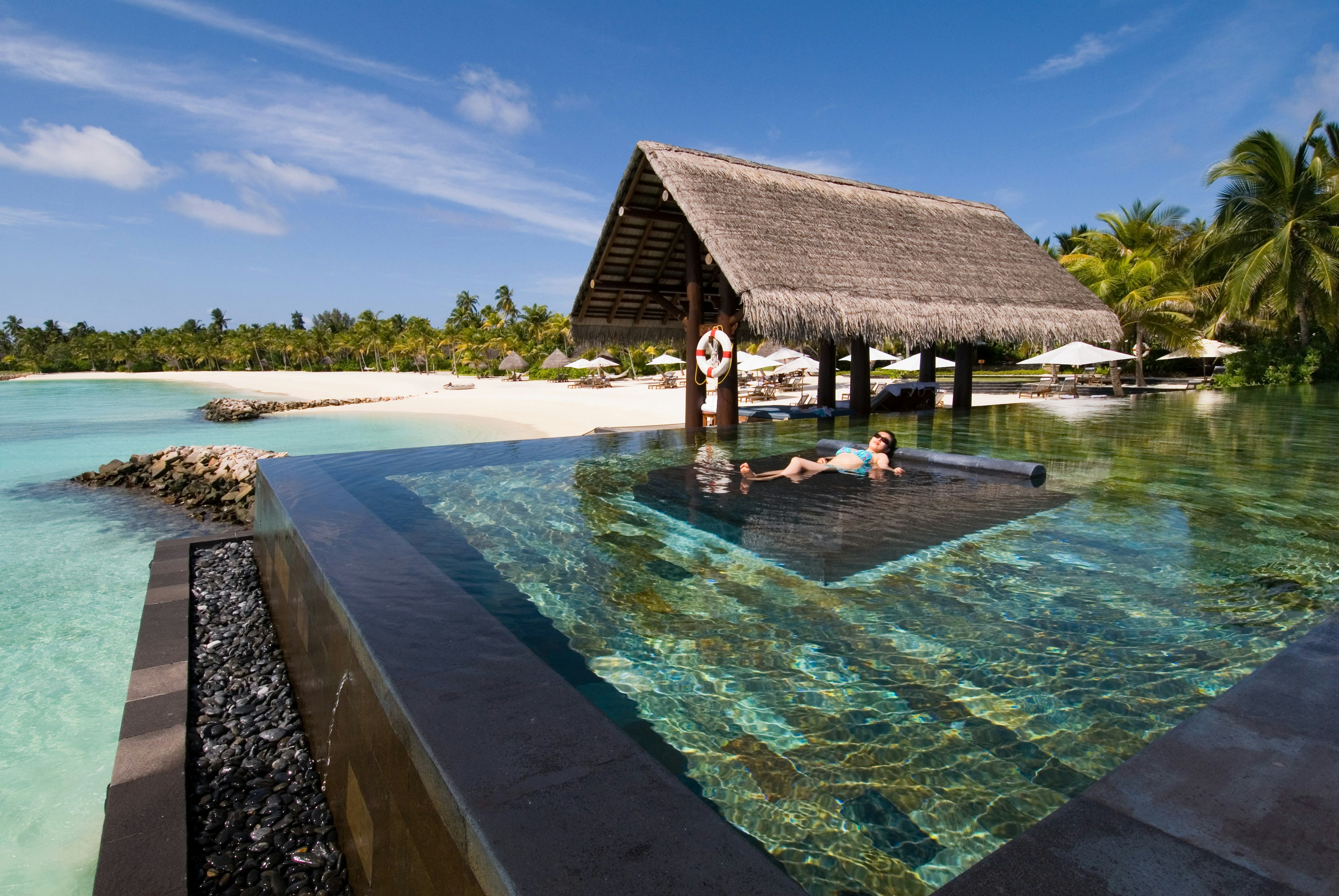 A woman lies in a resort infinity pool