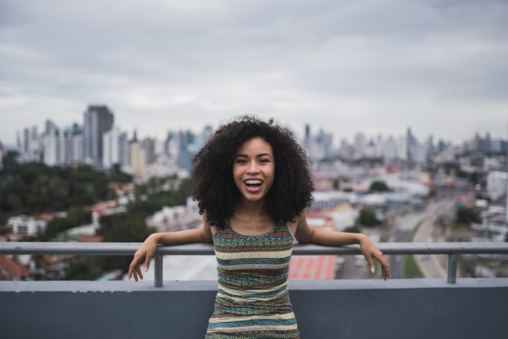 A young woman smiling on a balcony with Panama City in the background