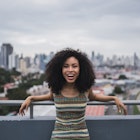 A young woman smiling on a balcony with Panama City in the background