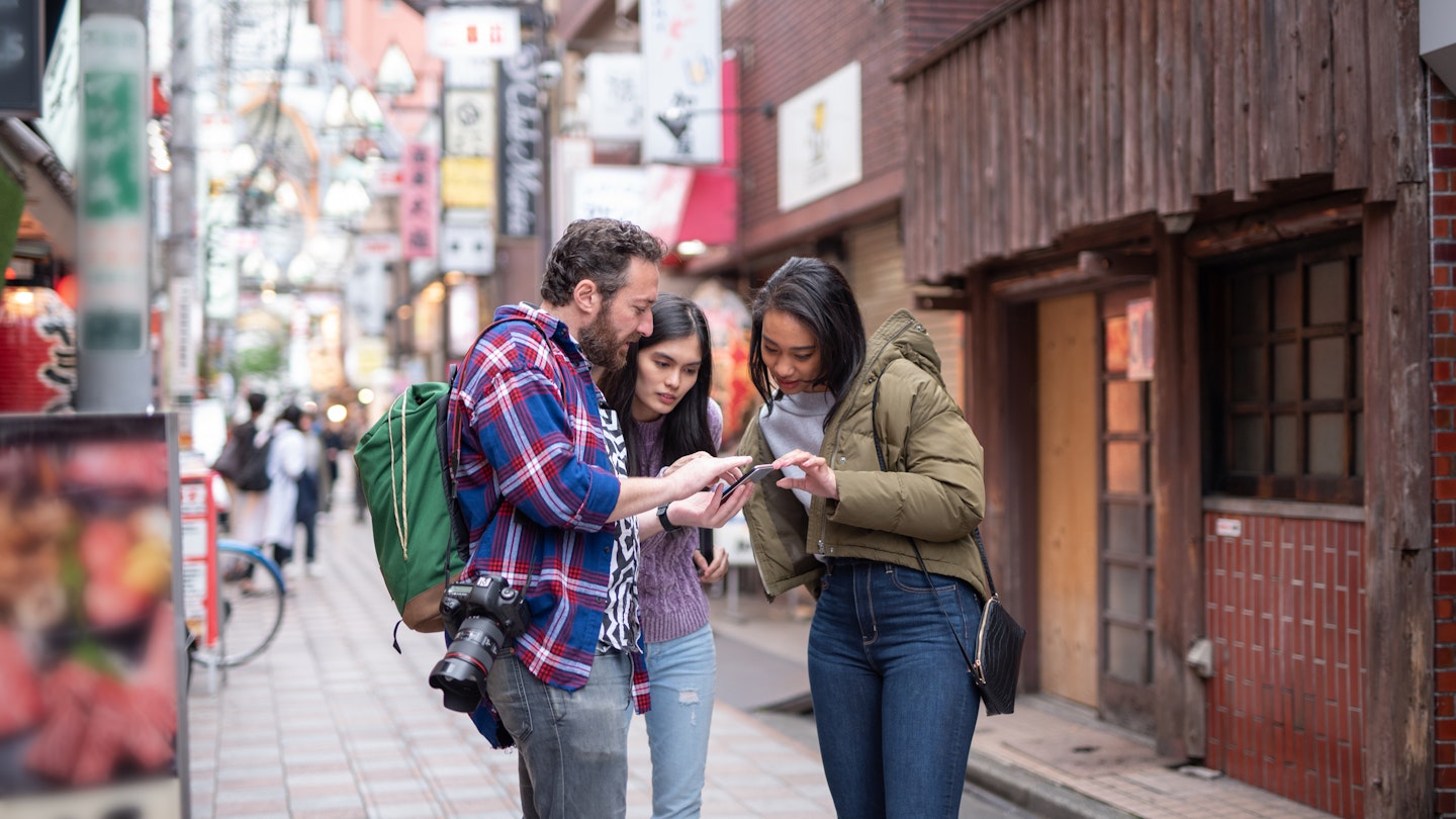 A tourist carrying a camera asks for directions in Tokyo, Japan