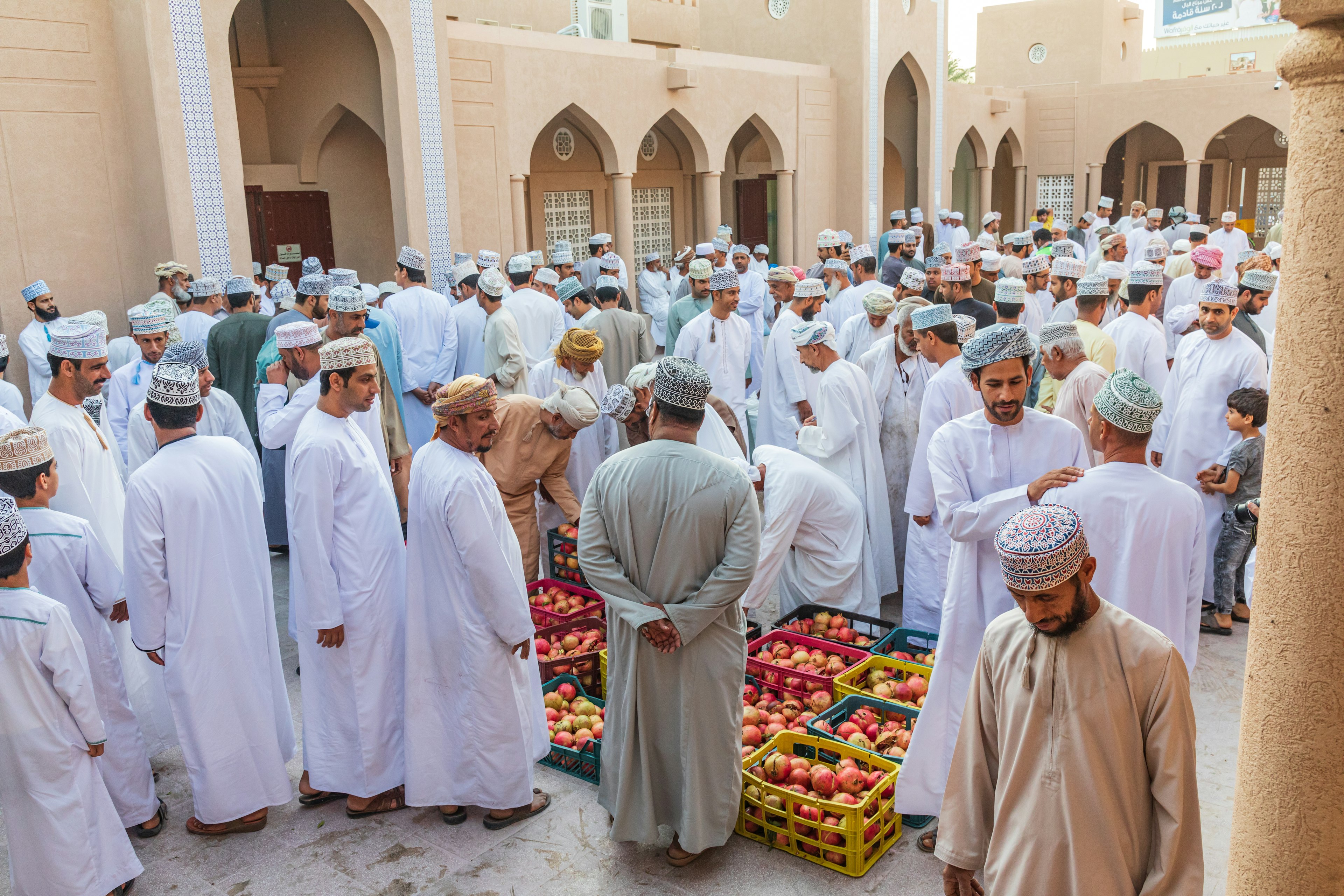 Men haggling over pomegranates at the souk in Nizwa, Oman